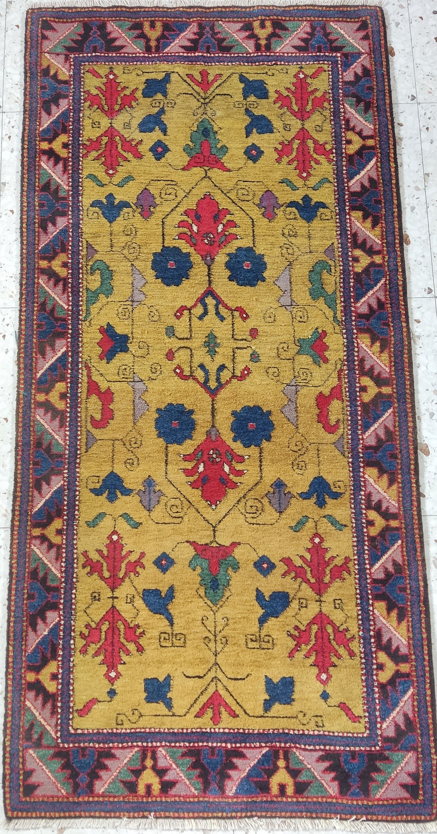 Anatolian yellow-ground rug with stylized floral motifs and stepped border, handwoven with natural-dyed wool.