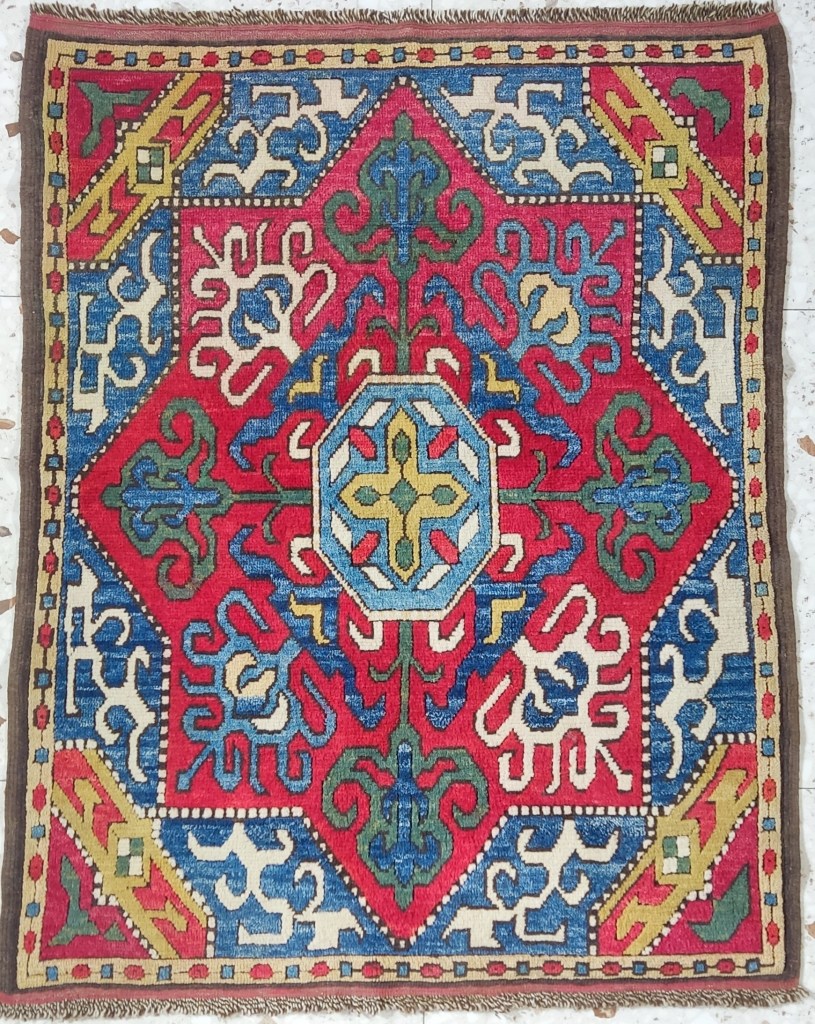 Handwoven Armenian rug with central octagonal medallion, red field, and geometric motifs in blue, ivory, green, and yellow.